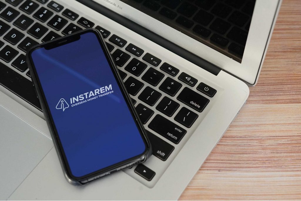 Instarem app on phone on top of laptop